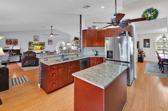 kitchen with appliances with stainless steel finishes, ceiling fan, a sink, vaulted ceiling, and open floor plan