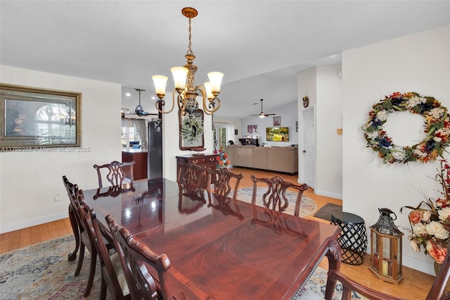 dining room featuring baseboards, light wood-type flooring, a chandelier, and a ceiling fan