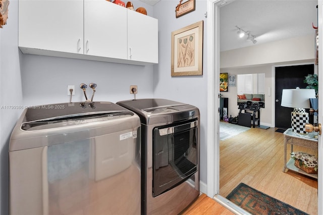 washroom featuring cabinet space, washing machine and dryer, and light wood-style floors