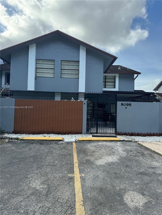 8098 NW 99th Ter, Hialeah Gardens, FL 33016 - view of side of home with stucco siding, uncovered parking, fence, and a gate