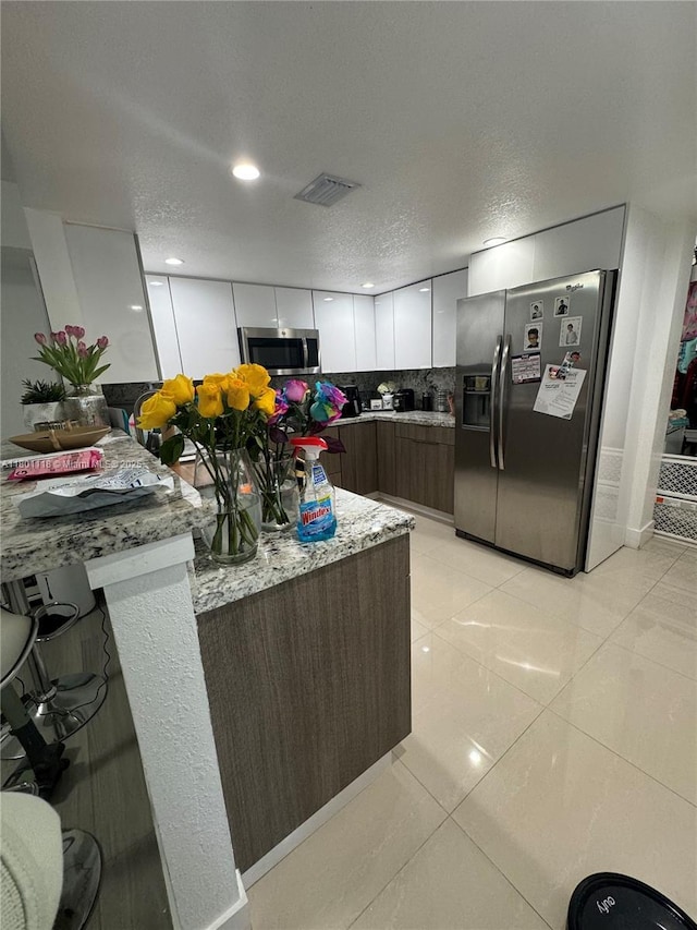 8098 NW 99th Ter, Hialeah Gardens, FL 33016 - kitchen featuring appliances with stainless steel finishes, decorative backsplash, light tile patterned floors, modern cabinets, and white cabinets