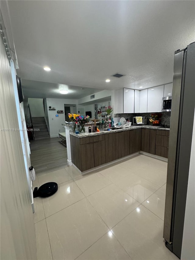 8098 NW 99th Ter, Hialeah Gardens, FL 33016 - kitchen with open floor plan, appliances with stainless steel finishes, a peninsula, white cabinets, and modern cabinets