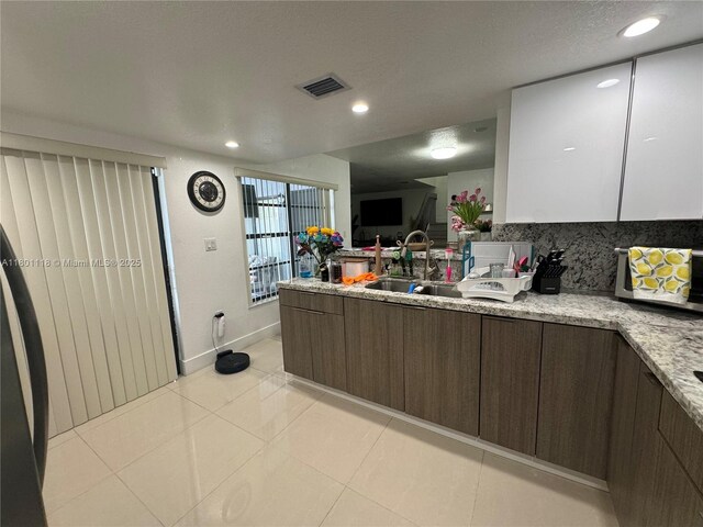8098 NW 99th Ter, Hialeah Gardens, FL 33016 - kitchen featuring a sink, a peninsula, baseboards, light tile patterned floors, and recessed lighting
