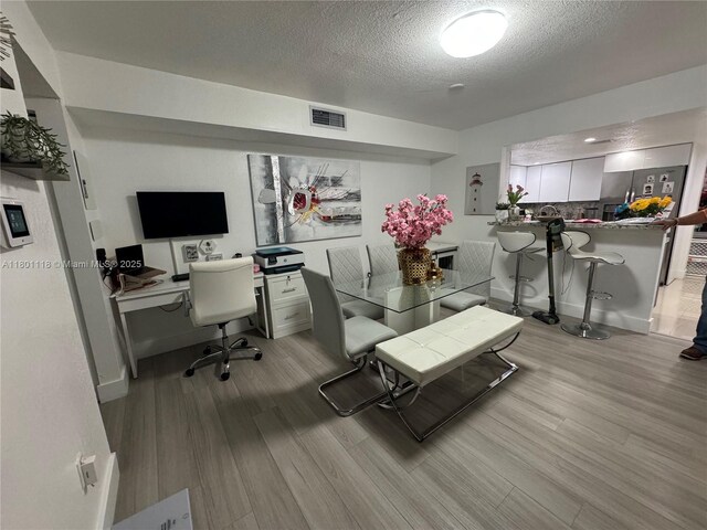 8098 NW 99th Ter, Hialeah Gardens, FL 33016 - dining area with wood finished floors, a textured ceiling, a desk, and baseboards
