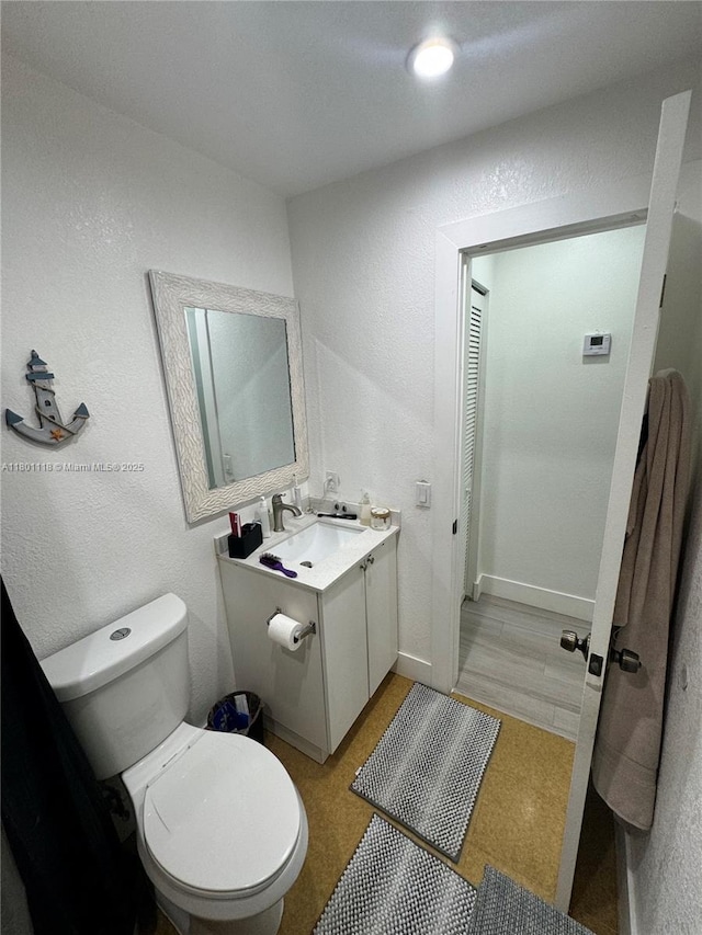 8098 NW 99th Ter, Hialeah Gardens, FL 33016 - bathroom featuring toilet, a textured wall, and vanity