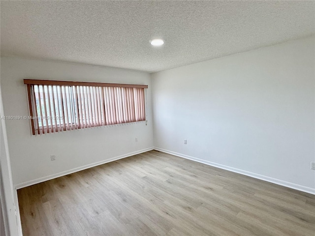 unfurnished room with wood finished floors, a textured ceiling, baseboards, and recessed lighting