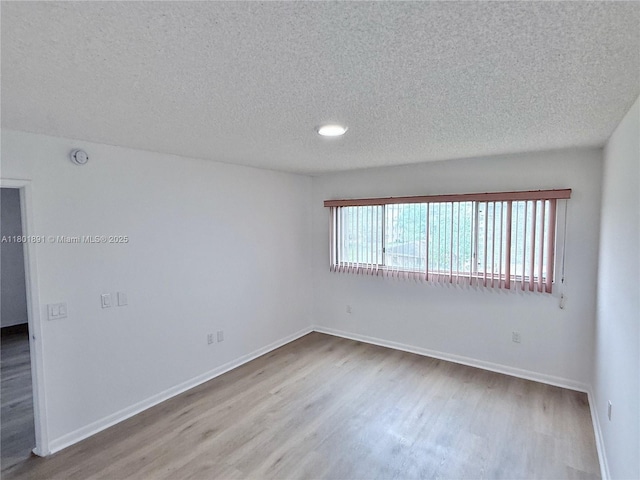 spare room featuring wood finished floors, a textured ceiling, baseboards, and a smoke detector
