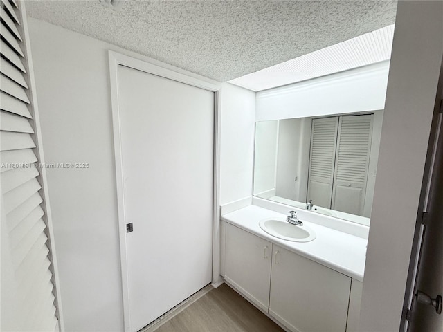 bathroom with wood finished floors, a textured ceiling, and vanity