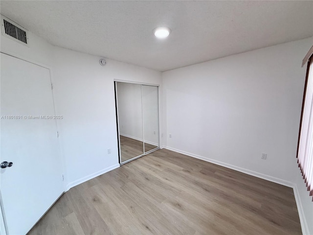 unfurnished bedroom featuring wood finished floors, a closet, and baseboards