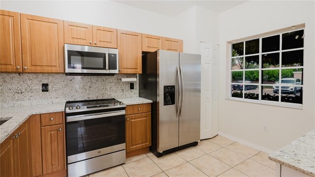 7818 Catalina Cir, Tamarac, FL 33321 - kitchen featuring appliances with stainless steel finishes, decorative backsplash, light tile patterned floors, and light stone countertops