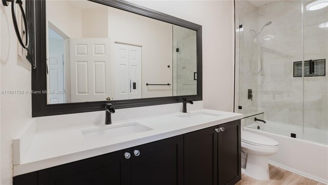 7818 Catalina Cir, Tamarac, FL 33321 - full bath featuring toilet, double vanity, combined bath / shower with glass door, and wood finished floors