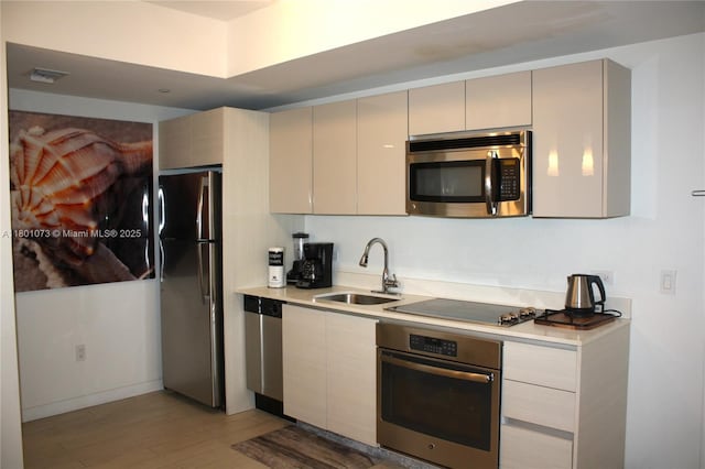 2602 E Hallandale Beach Blvd Unit R408, Hallandale Beach, FL 33009 - kitchen with stainless steel appliances, a sink, light wood finished floors, light countertops, and cream cabinets