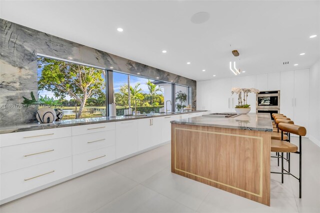 4430 Casper Ct, Hollywood, FL 33021 - kitchen featuring modern cabinets, a kitchen island, recessed lighting, white cabinets, and a kitchen bar