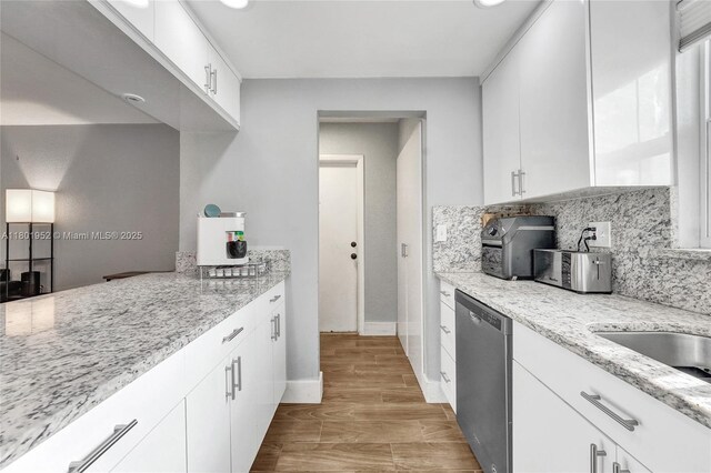 8504 Old Country Mnr Unit 205, Davie, FL 33328 - kitchen featuring stainless steel dishwasher, tasteful backsplash, white cabinets, light stone counters, and baseboards