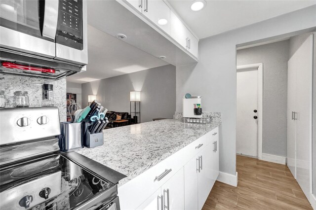 8504 Old Country Mnr Unit 205, Davie, FL 33328 - kitchen with appliances with stainless steel finishes, white cabinets, light wood-type flooring, light stone countertops, and baseboards