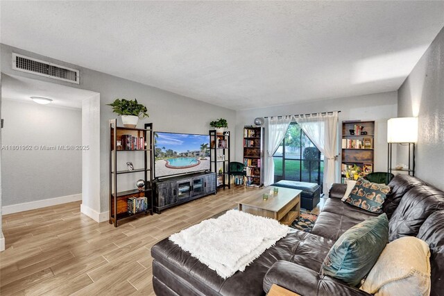 8504 Old Country Mnr Unit 205, Davie, FL 33328 - living room with light wood-style flooring, baseboards, and a textured ceiling