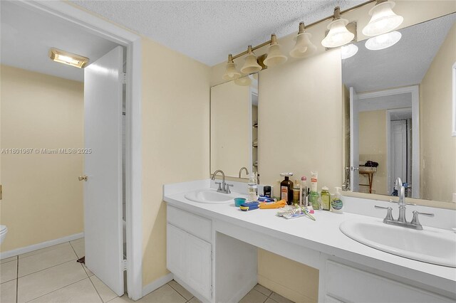 1458 N Lawnwood Cir Unit 24, Fort Pierce, FL 34950 - bathroom with tile patterned floors, double vanity, a textured ceiling, toilet, and baseboards