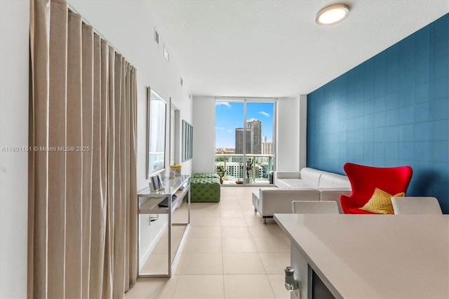 living area with floor to ceiling windows, a view of city, and light tile patterned flooring