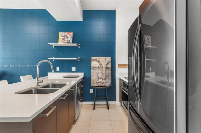 kitchen featuring stainless steel appliances, a sink, light tile patterned floors, light countertops, and modern cabinets