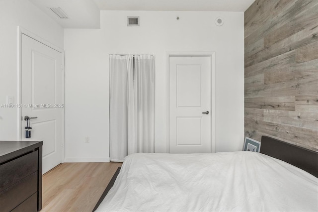 bedroom with light wood finished floors and wood walls
