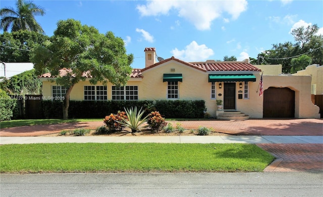 804 SE 10th St, Fort Lauderdale, FL 33316 - mediterranean / spanish home featuring a tiled roof, decorative driveway, stucco siding, a chimney, and a front lawn