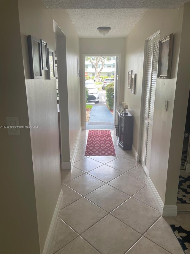 7680 NW 18th St Unit 107, Margate, FL 33063 - corridor with light tile patterned floors, a textured ceiling, and baseboards