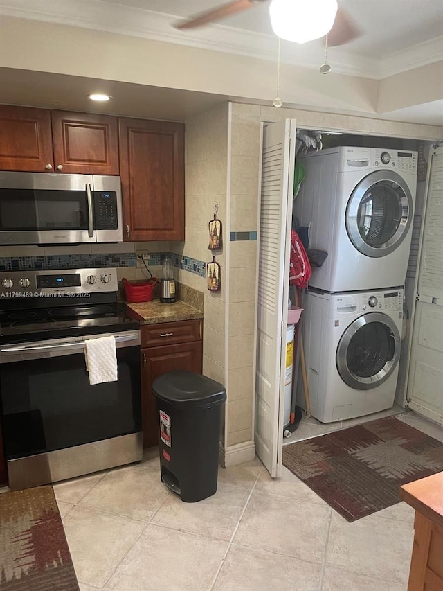 7680 NW 18th St Unit 107, Margate, FL 33063 - kitchen featuring stainless steel appliances, stacked washing machine and dryer, ornamental molding, light tile patterned floors, and ceiling fan