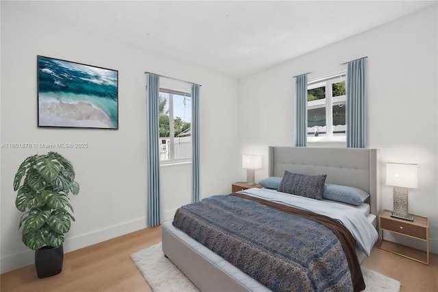 bedroom with light wood-style floors, multiple windows, and baseboards