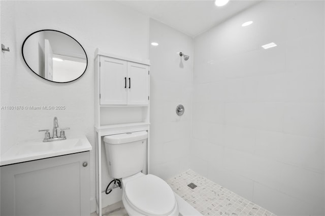 bathroom with tiled shower, toilet, vanity, and recessed lighting