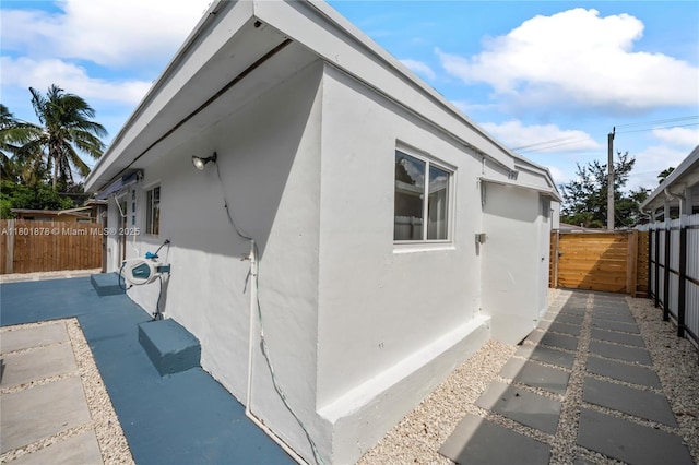 view of side of property featuring stucco siding and fence