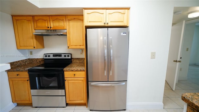 kitchen with stainless steel appliances, under cabinet range hood, light tile patterned floors, and dark stone counters