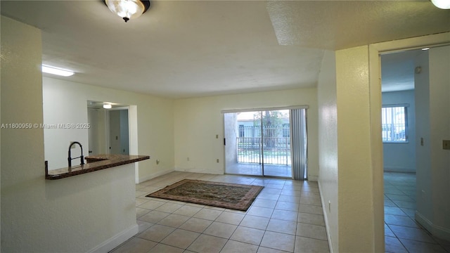 doorway with light tile patterned floors, a sink, and baseboards