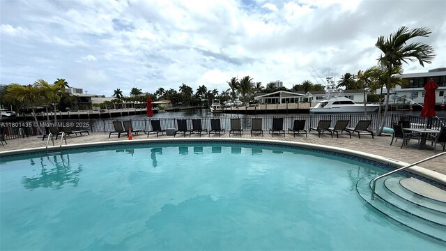 301 Golden Isles Dr Unit 203, Hallandale Beach, FL 33009 - community pool with fence, a water view, and a patio