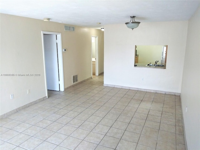 spare room featuring light tile patterned flooring and baseboards