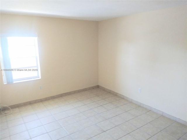 unfurnished room featuring baseboards and light tile patterned floors