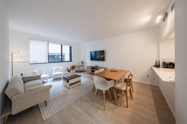 dining space with light wood-type flooring and baseboards