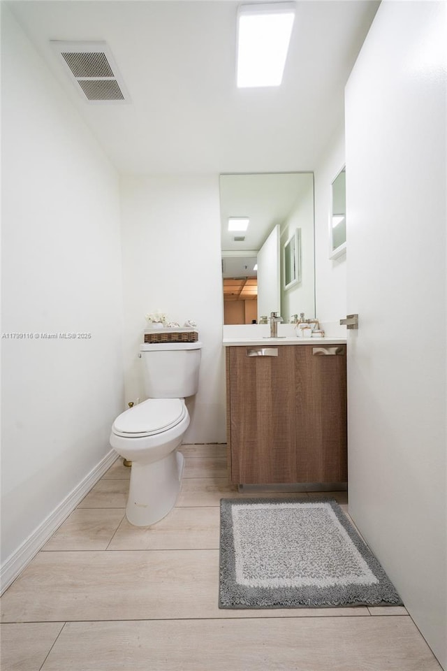 half bath featuring toilet, vanity, and wood finished floors