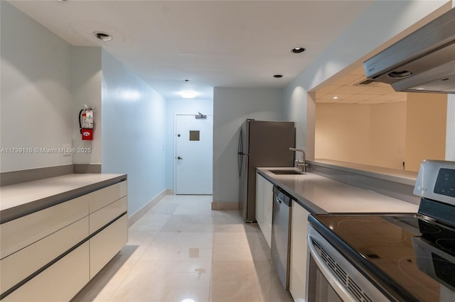 kitchen featuring appliances with stainless steel finishes, ventilation hood, a sink, baseboards, and white cabinetry