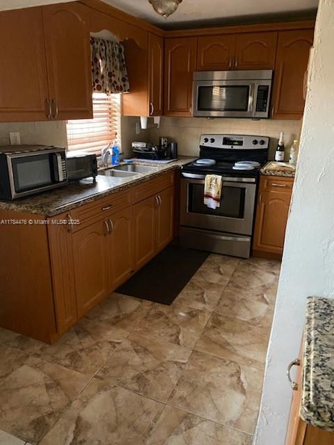 kitchen with stainless steel appliances, a sink, and brown cabinetry