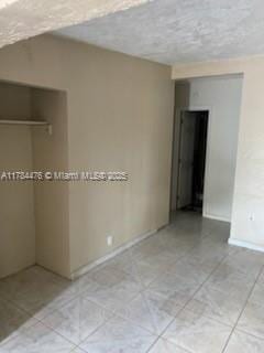 unfurnished room featuring light tile patterned floors, a textured ceiling, and baseboards