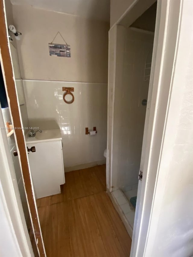 bathroom with wood finished floors, a shower stall, vanity, and toilet