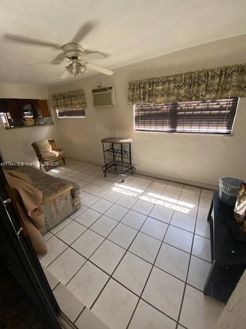 living room with light tile patterned floors, a ceiling fan, and a wall mounted air conditioner
