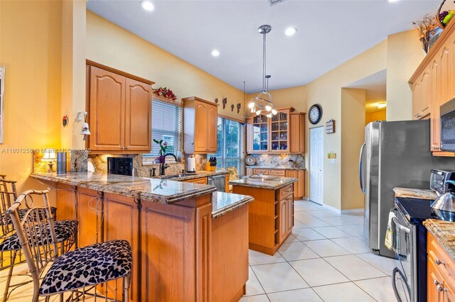 16343 Segovia Cir S, Pembroke Pines, FL 33331 - kitchen with stainless steel appliances, a sink, tasteful backsplash, a peninsula, and light stone countertops
