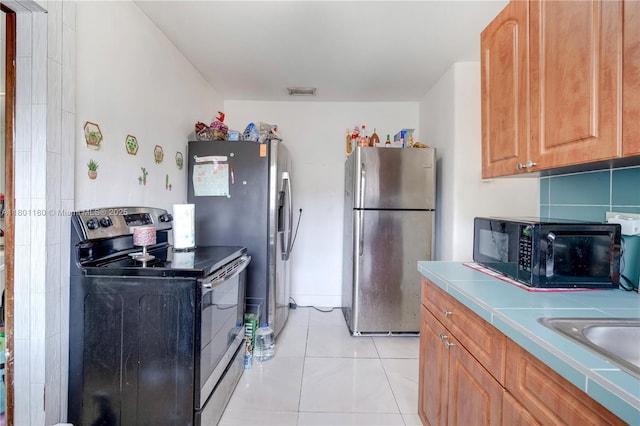 3050 NW 22nd Ct, Miami, FL 33142 - kitchen featuring appliances with stainless steel finishes, backsplash, tile countertops, a sink, and light tile patterned flooring