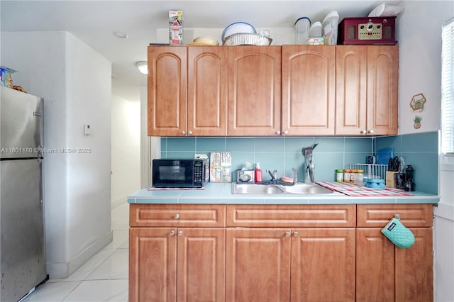 3050 NW 22nd Ct, Miami, FL 33142 - kitchen with black microwave, freestanding refrigerator, a sink, light tile patterned floors, and tasteful backsplash