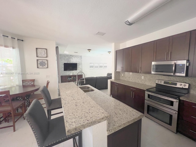 19994 SW 129th Ct, Miami, FL 33177 - kitchen featuring appliances with stainless steel finishes, dark brown cabinetry, open floor plan, light stone counters, and tasteful backsplash