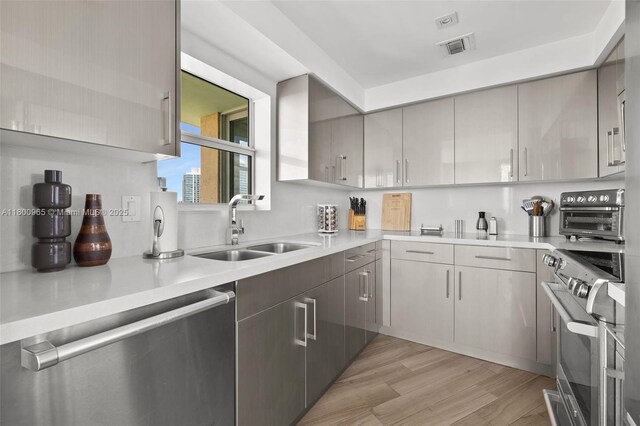 2475 Brickell Ave Unit 2002, Miami, FL 33129 - kitchen with stainless steel appliances, a sink, light countertops, light wood finished floors, and gray cabinetry