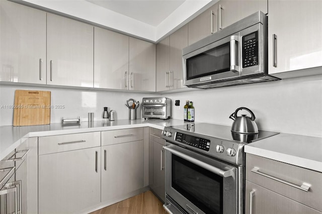 2475 Brickell Ave Unit 2002, Miami, FL 33129 - kitchen featuring appliances with stainless steel finishes, gray cabinetry, light countertops, and light wood-style flooring