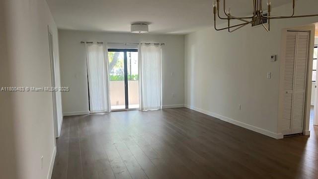 spare room with a chandelier, baseboards, and wood finished floors