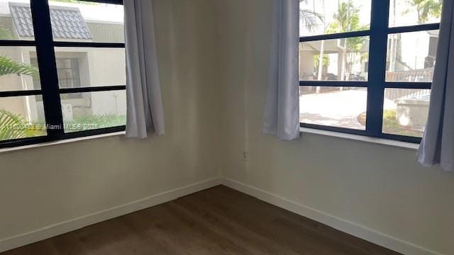 spare room featuring baseboards, healthy amount of natural light, and dark wood finished floors